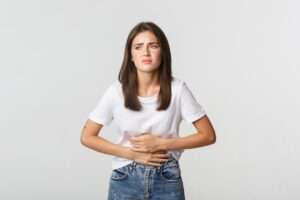 woman having stomach ache bending with hands belly discomfort from menstrual cramps 1258 19063