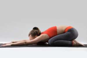 young attractive woman balasana pose grey studio background 1