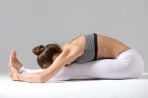 young woman paschimottanasana pose grey studio background 1